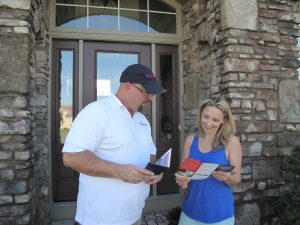 Man in white shirt and cap discussing exterior cleaning services with woman in blue top outside brick building in Fond du Lac, Wisconsin