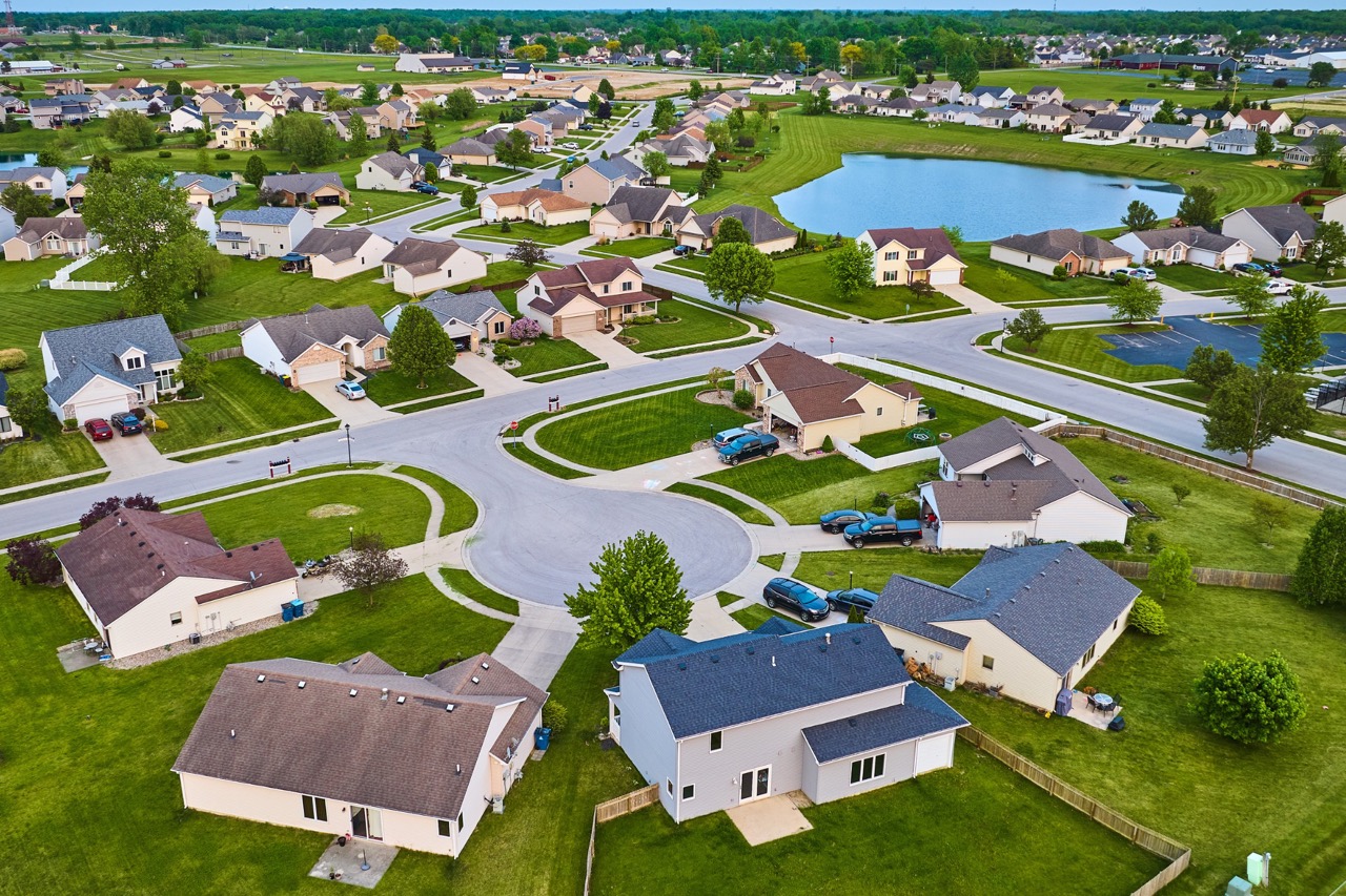 Aerial view of a suburban neighborhood in Fond du Lac, Wisconsin with well-maintained single-family homes, manicured lawns, curved streets, and decorative ponds