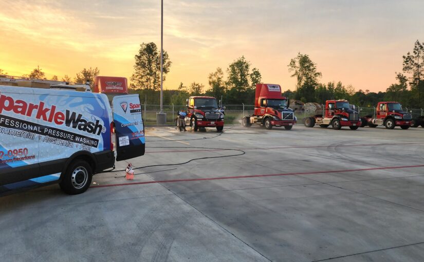 Sparkle Wash professional pressure washing service vehicle parked beside a fleet of red trucks at a commercial washing facility in Texarkana during sunset