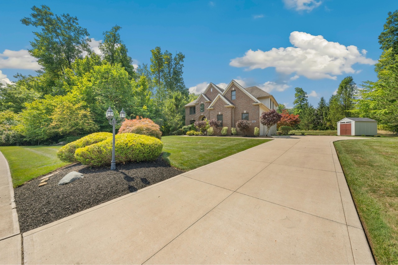 Residential driveway and sidewalk in Fond du Lac showing clean concrete pathways leading to brick home with manicured landscaping and detached garage