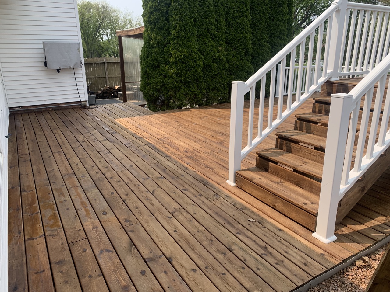 Newly cleaned wooden deck with white railings and stairs, showing freshly pressure washed surface in Fond du Lac, Wisconsin